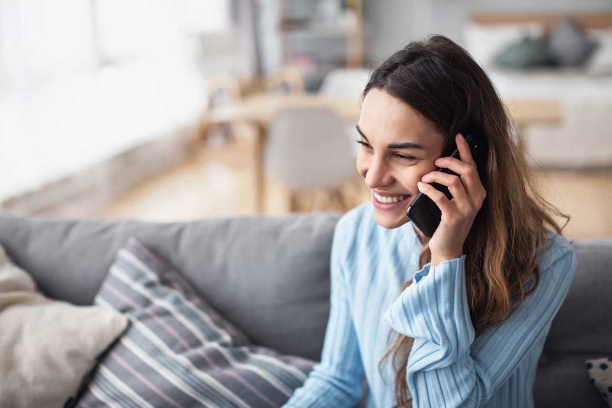 Attractive smiling woman talking on the phone at home. Technology, communication and coziness concept.