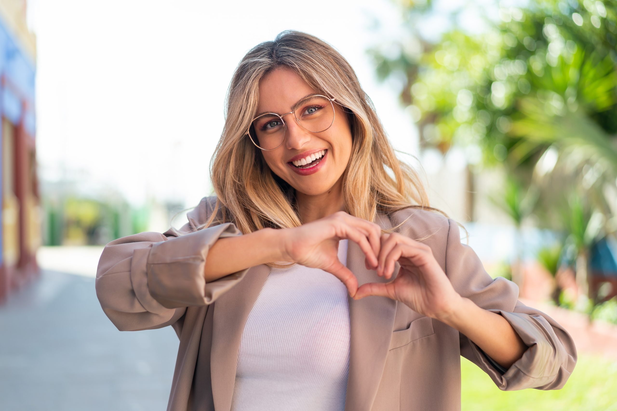 Pretty blonde Uruguayan woman With glasses making heart with hands